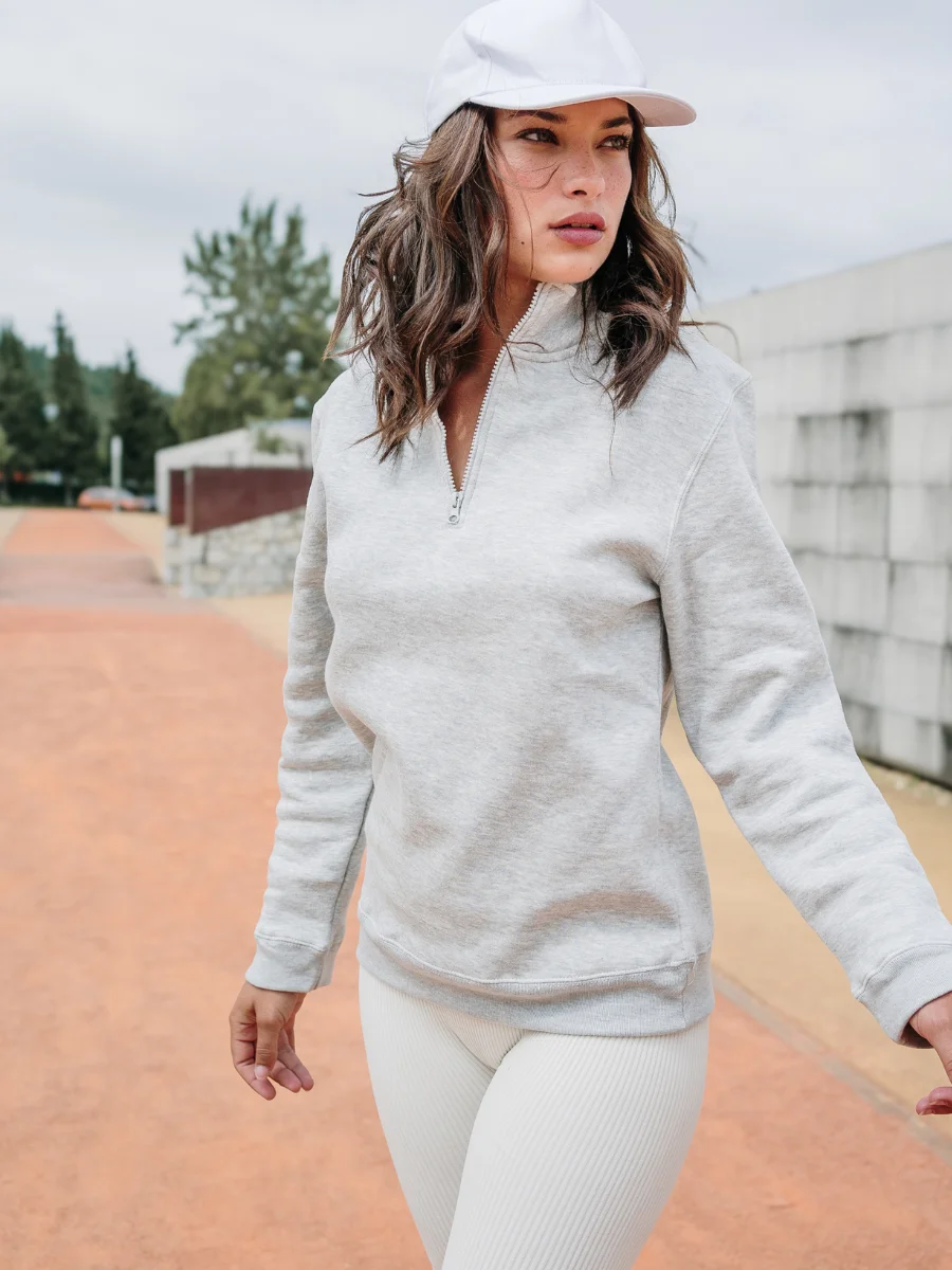 Dame trägt hellgraues TH Clothes Sweatshirt mit Reißverschluss beim Spaziergang im Freien